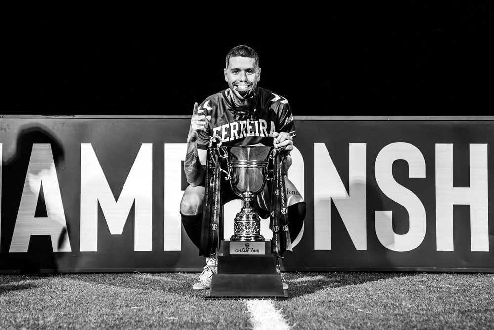 Luke kneeling on the pitch with a trophy and medal, Flower City Union FC, 2023